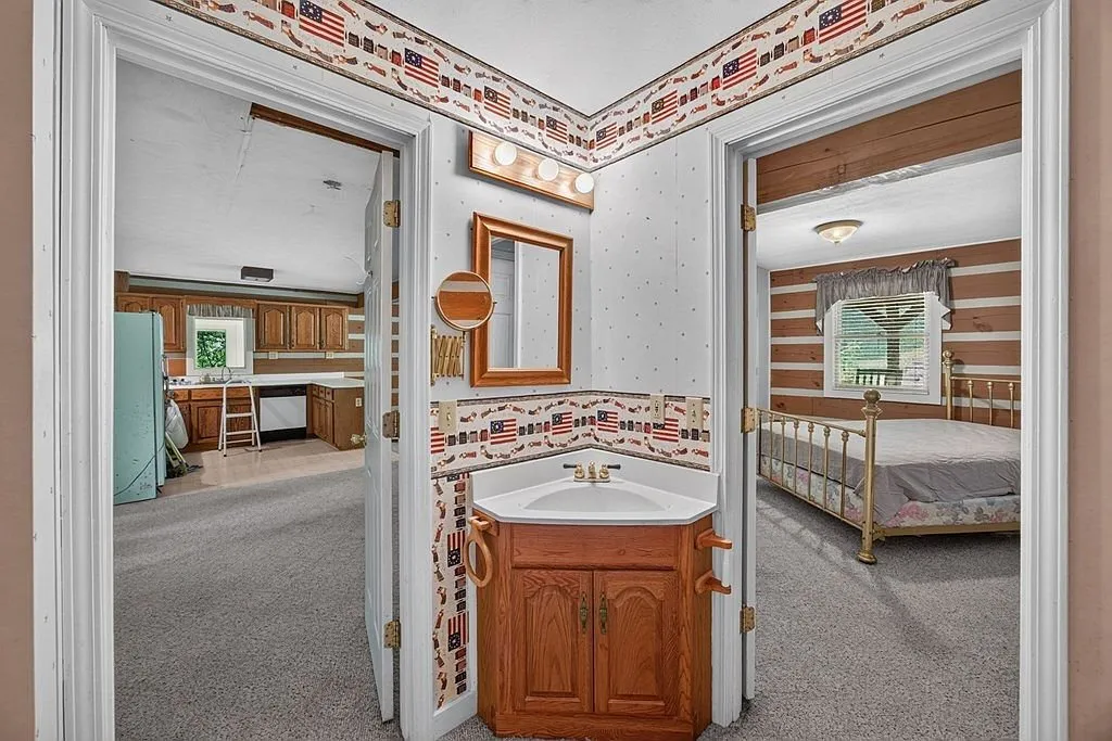 A hallway bathroom with a vanity and tiled accents