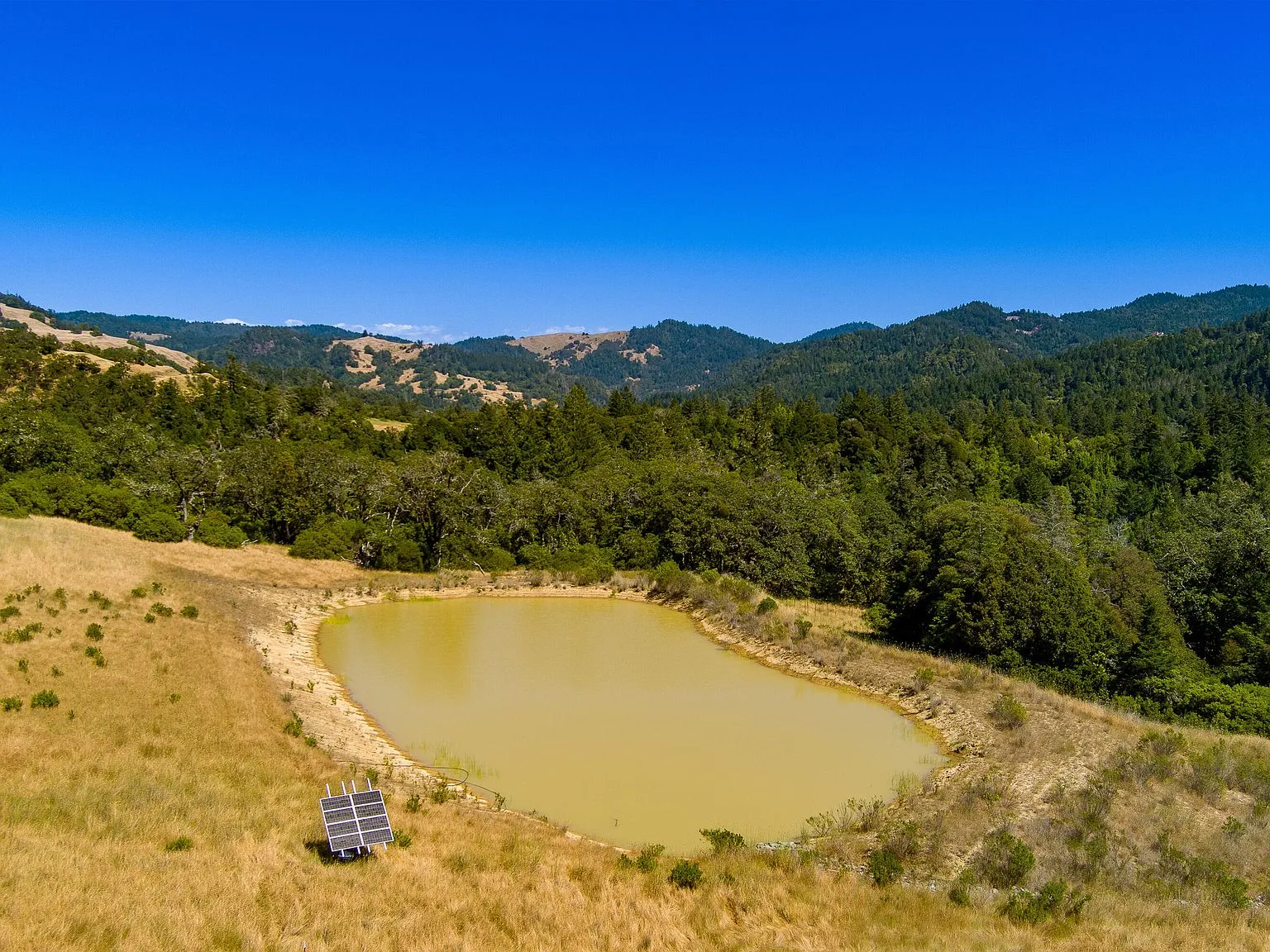 A second aerial view of the permitted pond in its hillside meadow setting