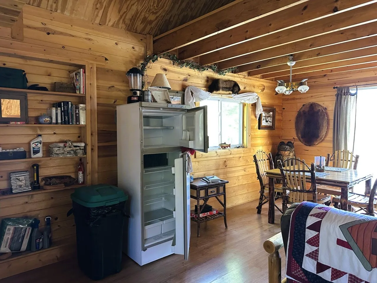 The kitchen area with refrigerator and shelving along the log wall