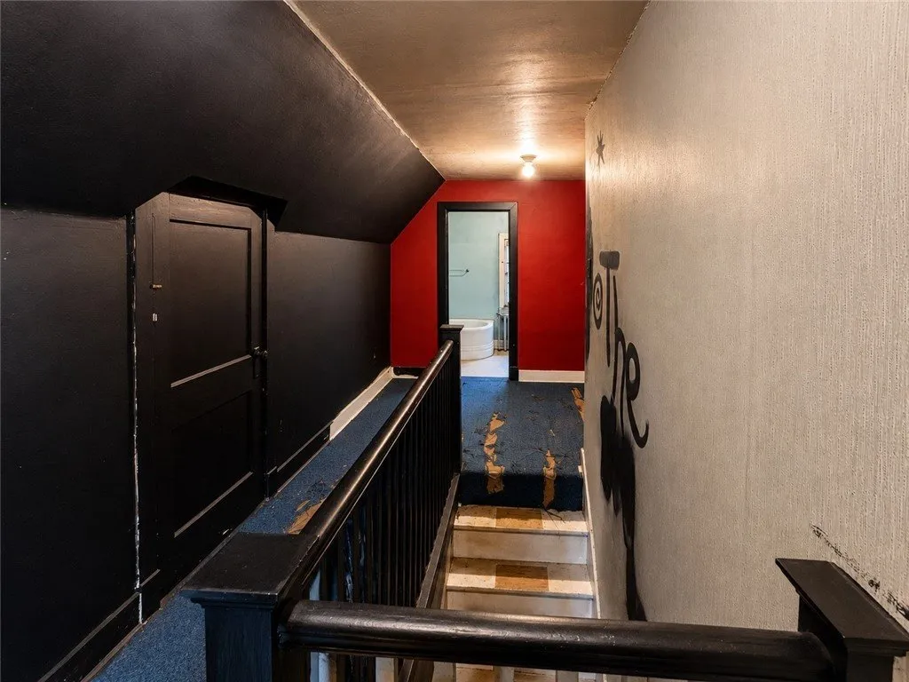 The stair to the third floor with dark walls and a red room beyond