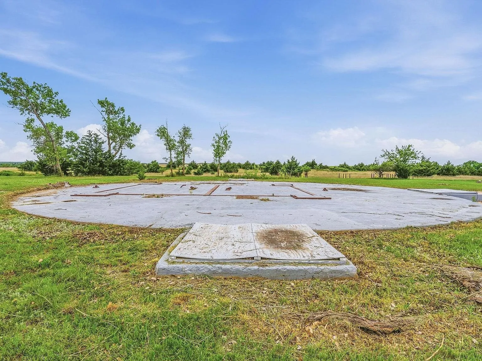 The large circular concrete pad at ground level, set into the surrounding lawn