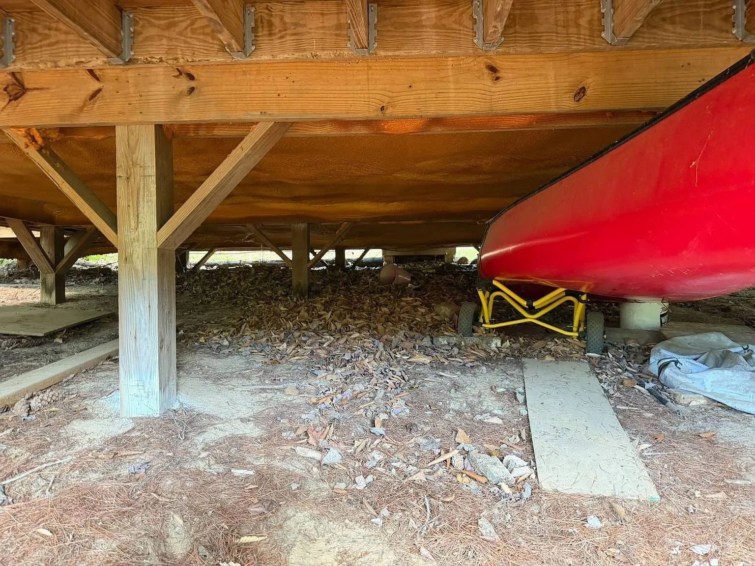 The space under the chalet with the posts and a red canoe