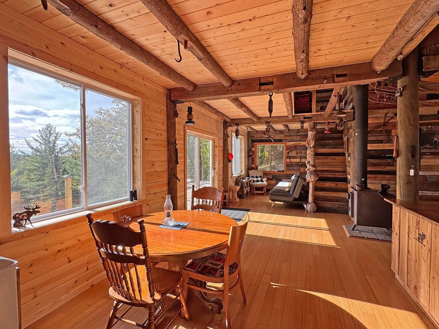 The dining table and chairs by the window, log walls around