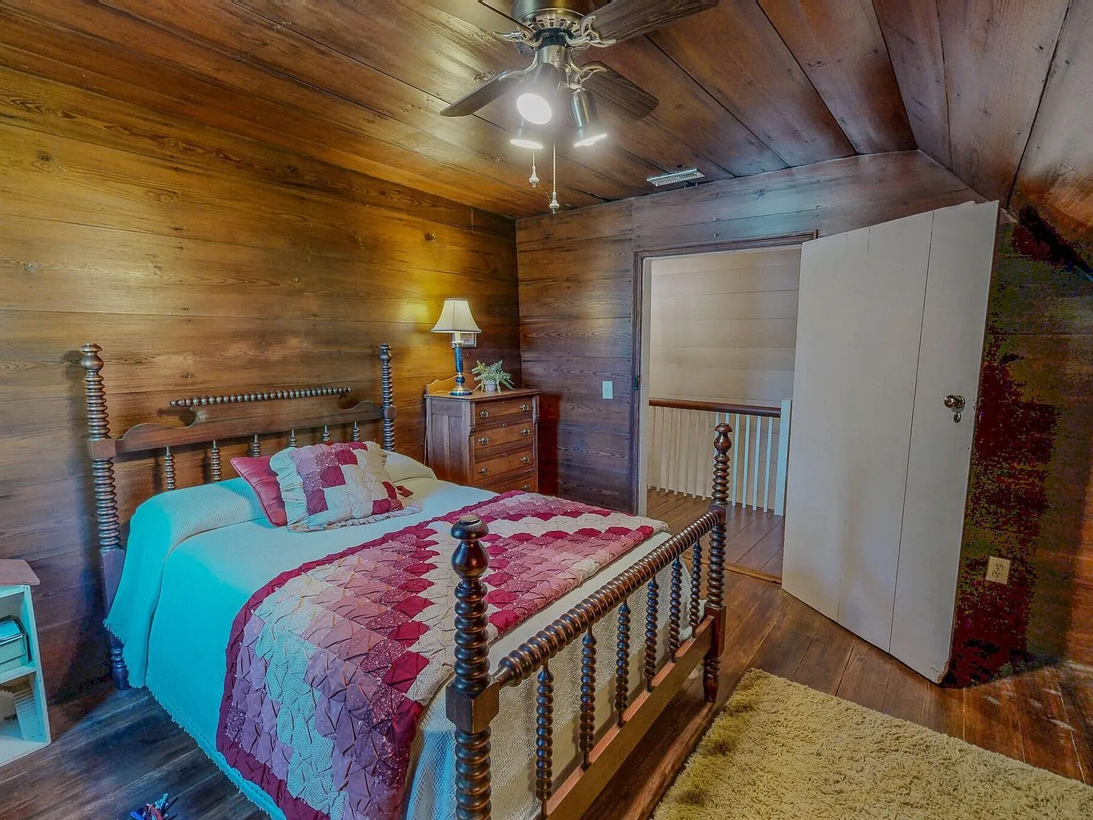 A second wood-paneled bedroom with a spindle bed and nightstand