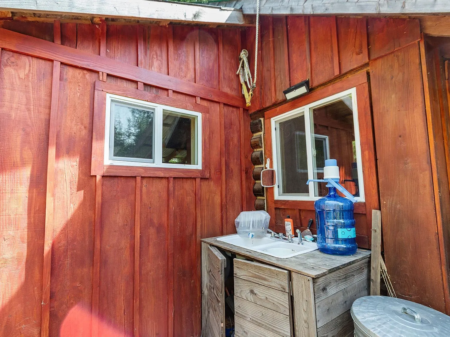 A water collection jug and storage cabinet tucked against the cabin's exterior wall