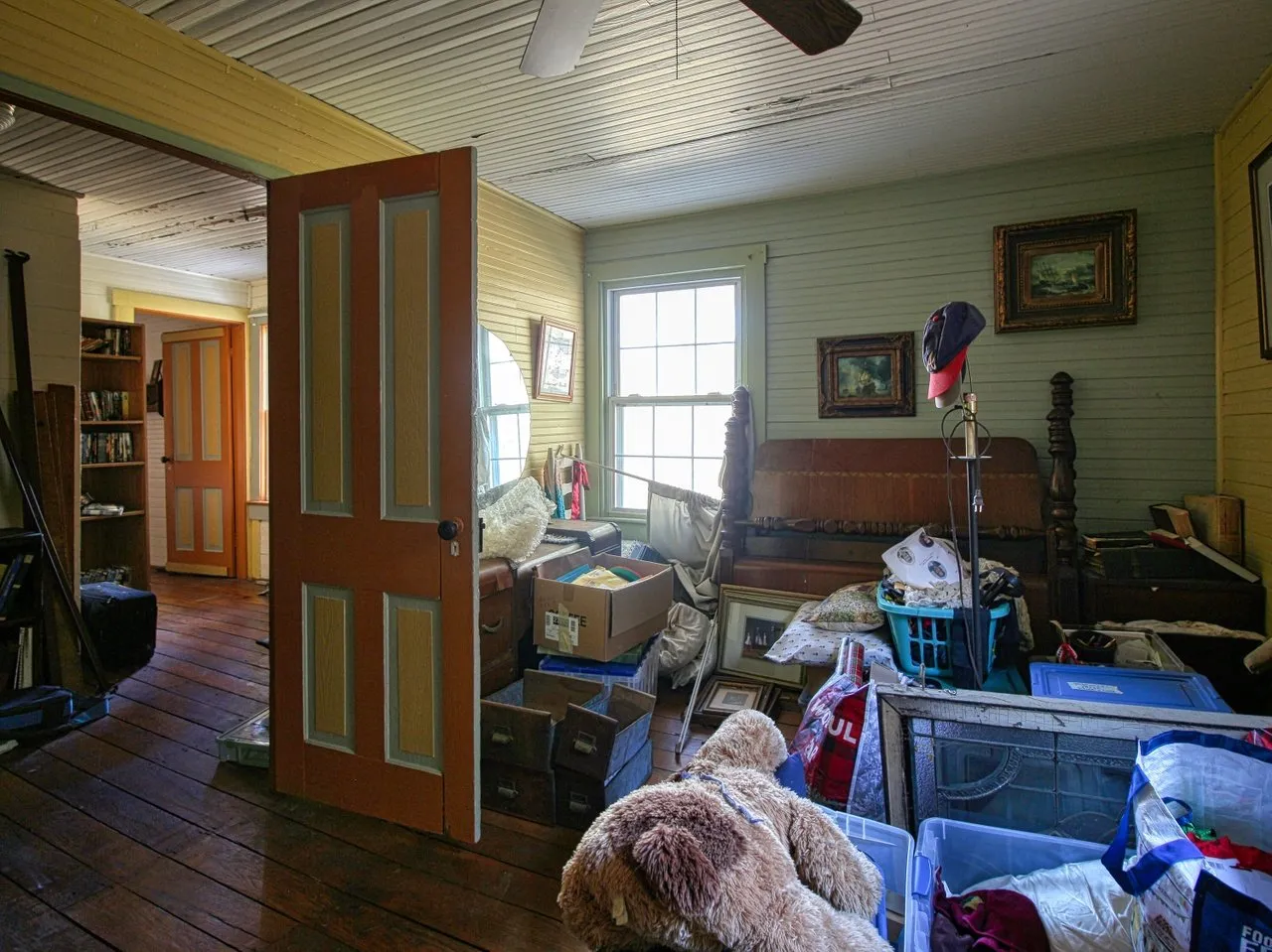 An upstairs room with painted doors, a bed and boxes