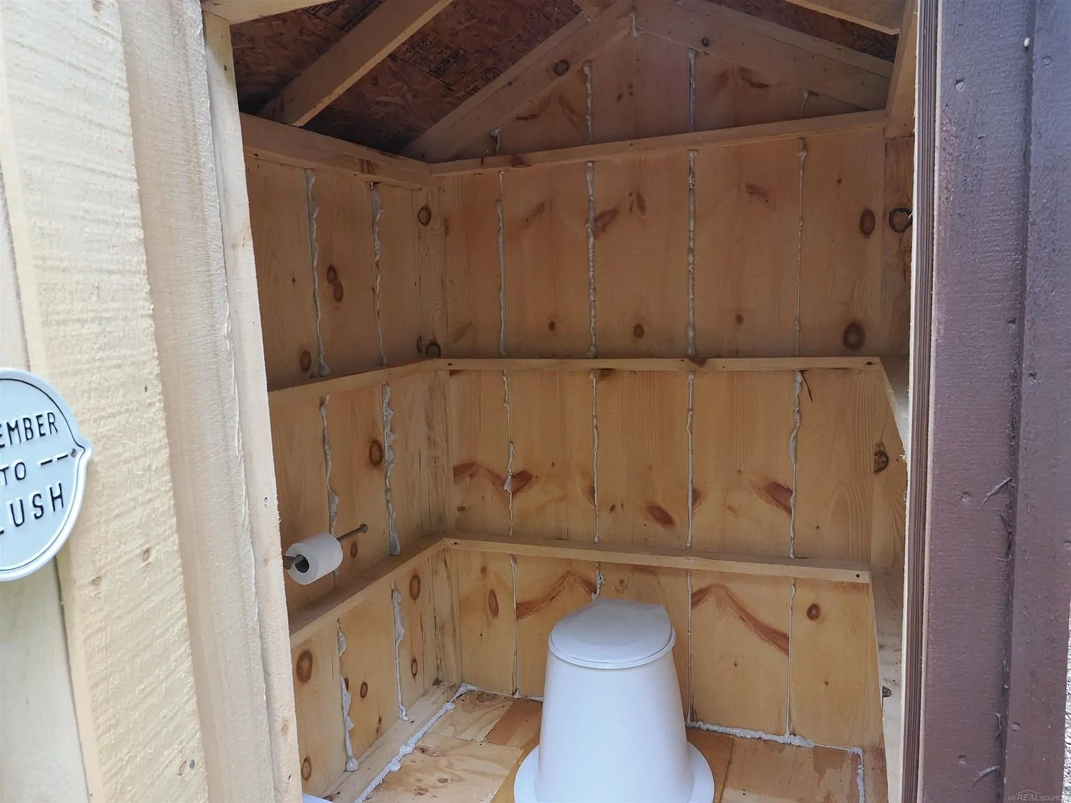 Inside the outhouse with the seat and the paper