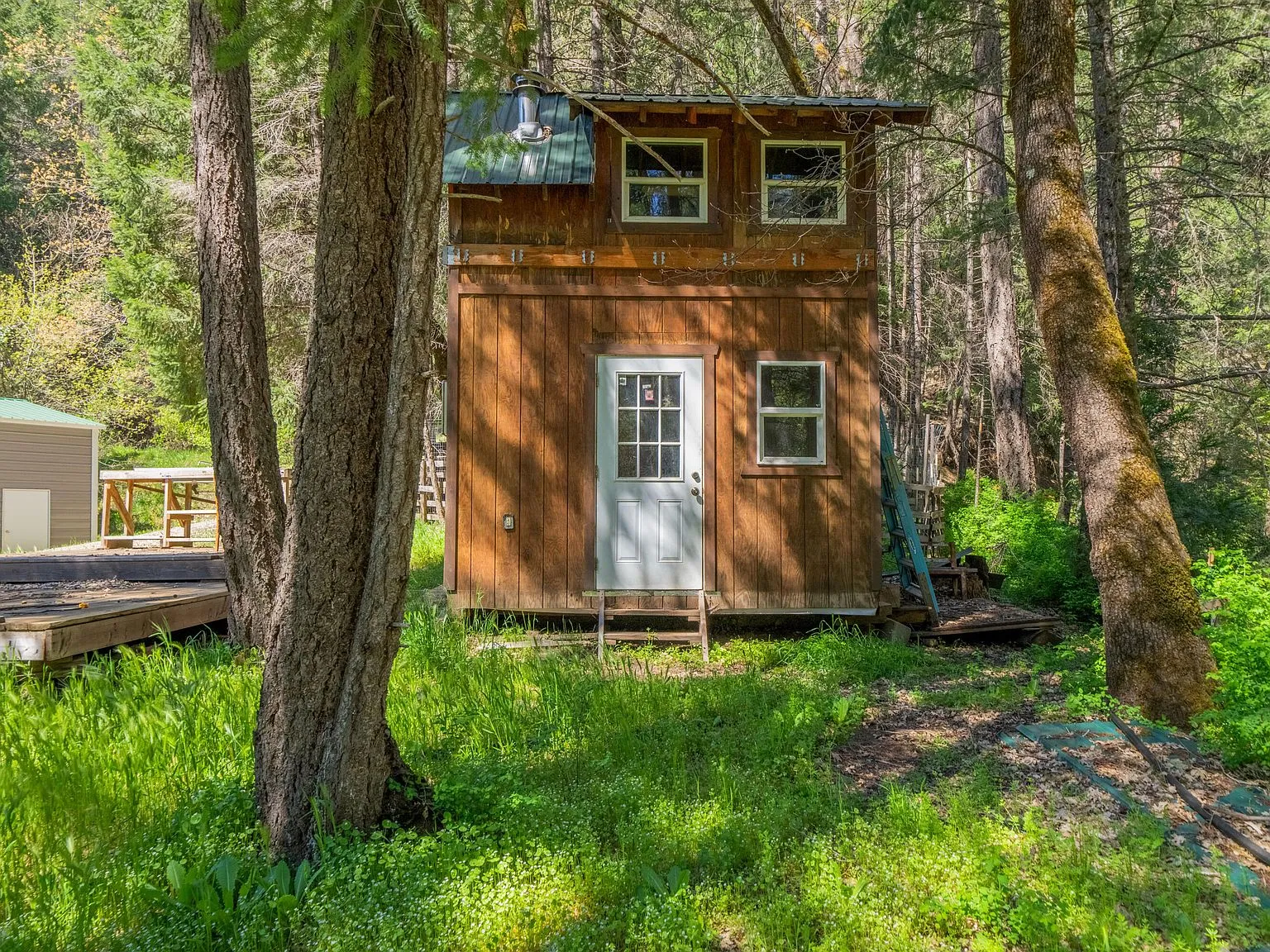 A small wood cabin structure with a covered porch, set among the trees