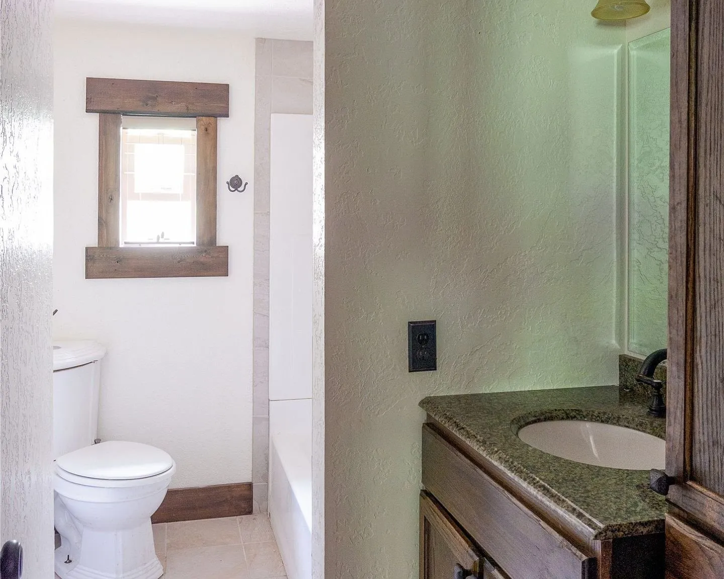 A bathroom with a granite-topped vanity and tiled tub surround