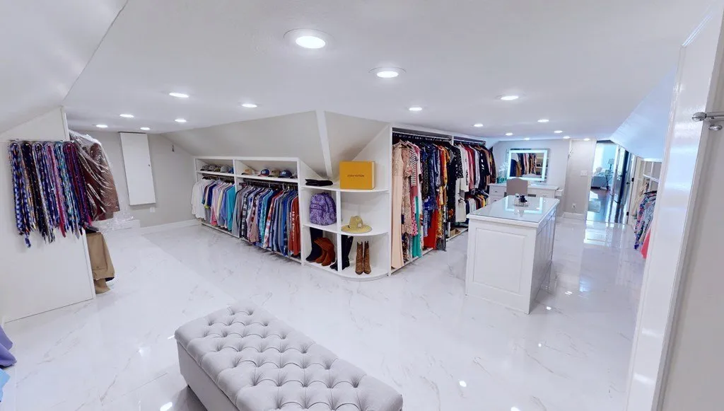 The walk-in closet fitted out with racks, shelving and a bench