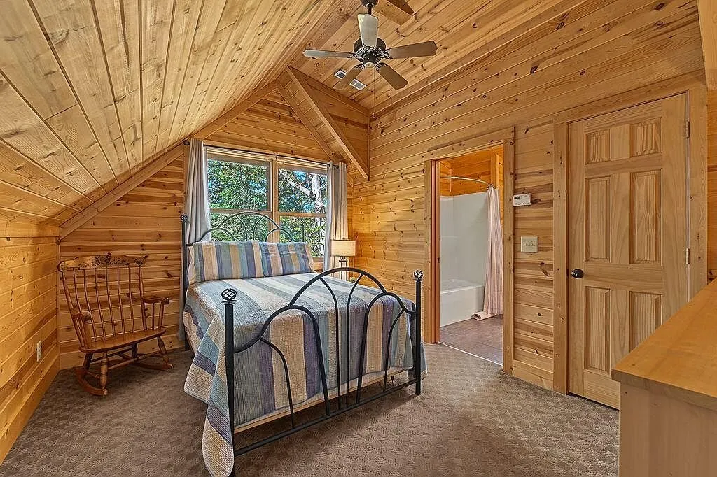 The upstairs bedroom under the sloped log ceiling with an en suite bath