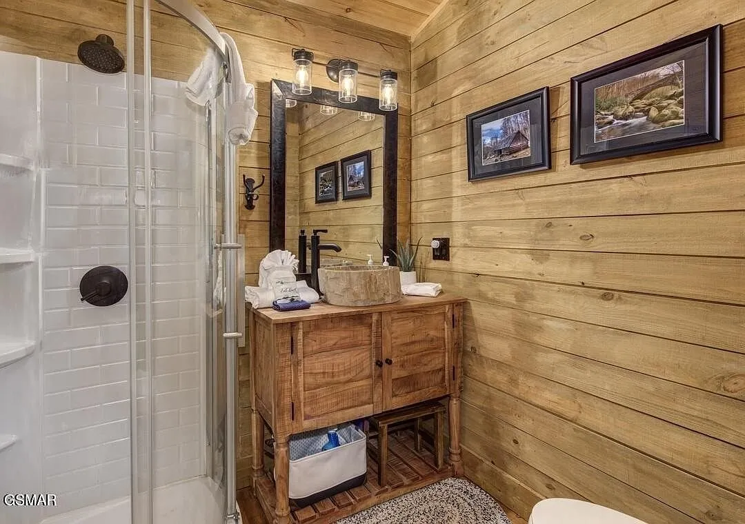 A bathroom with a corner shower and a wood vanity under a mirror