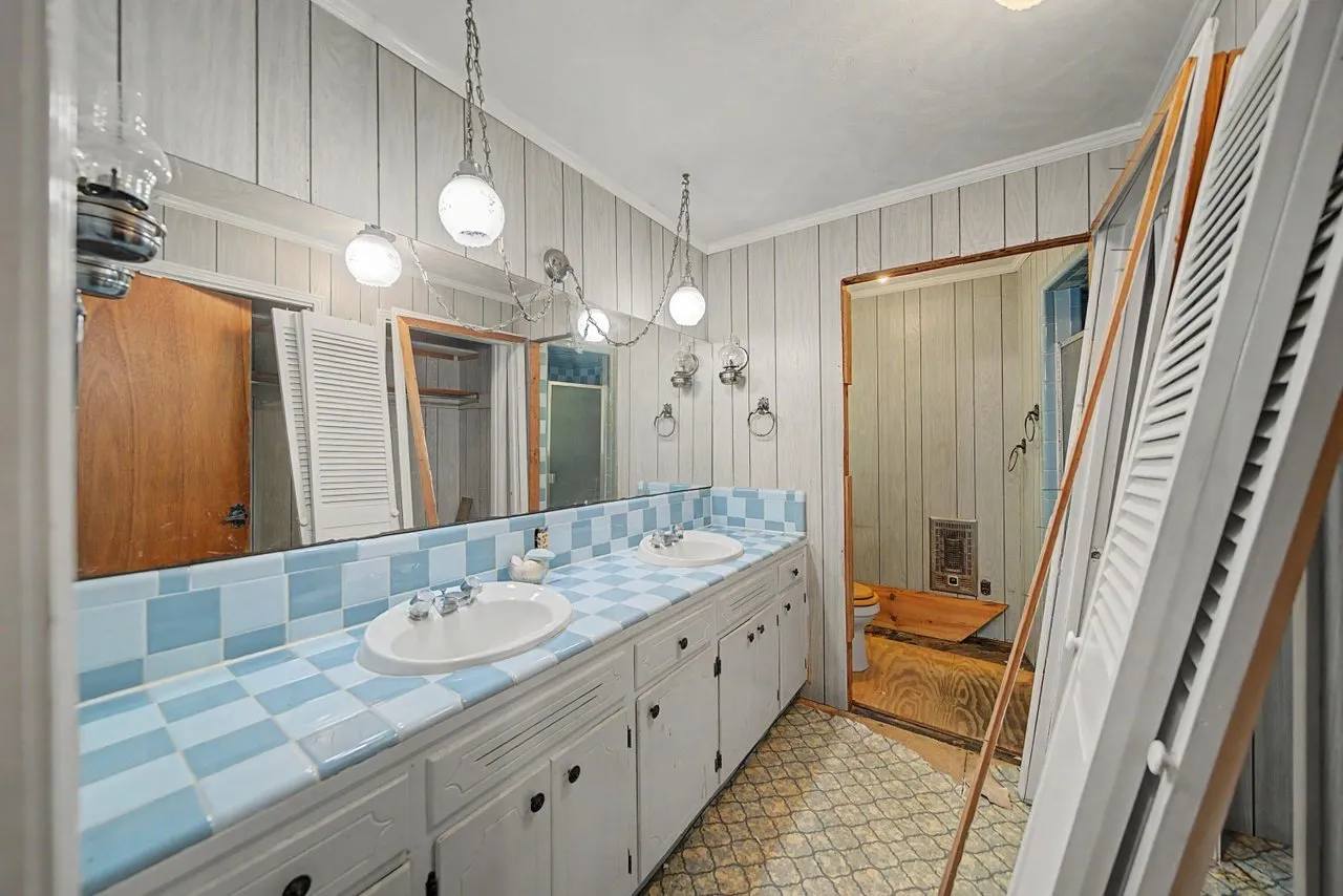 A long bathroom with a double vanity, tiled counter and mirrors