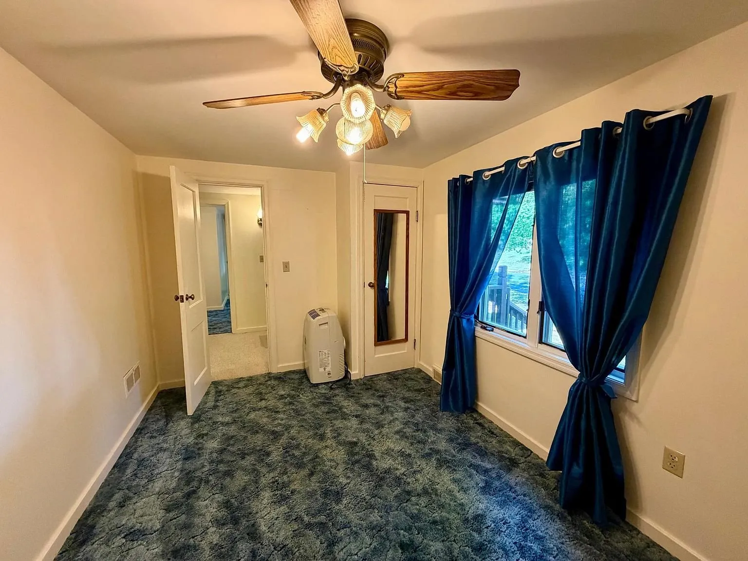 A bedroom with blue carpet and blue curtains
