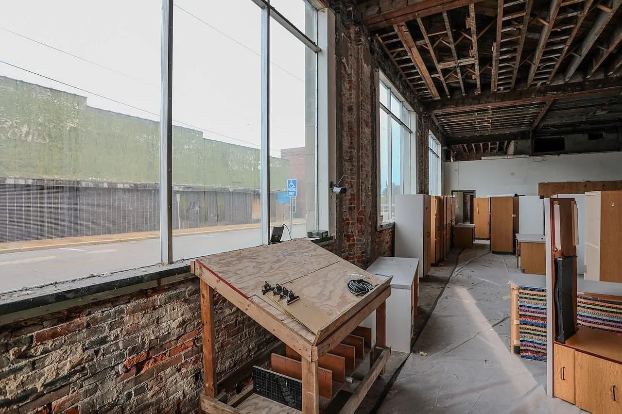 The ground floor gutted to exposed brick and open joists, office furniture stacked by the windows