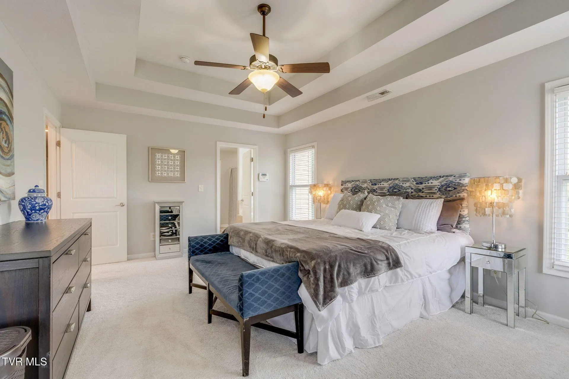 The primary bedroom from the far corner with the dressers and mirror
