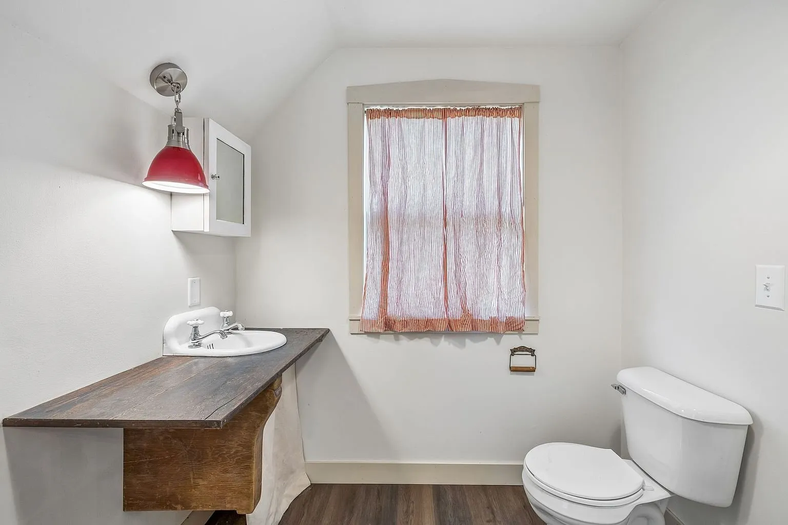 A bathroom with the counter sink, the red lamp and the window
