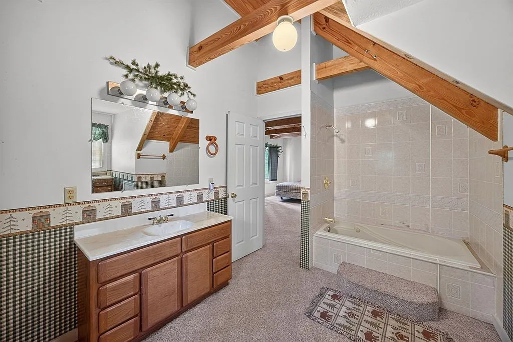 A bathroom with a tile floor, vanity and walk-in shower under the roofline