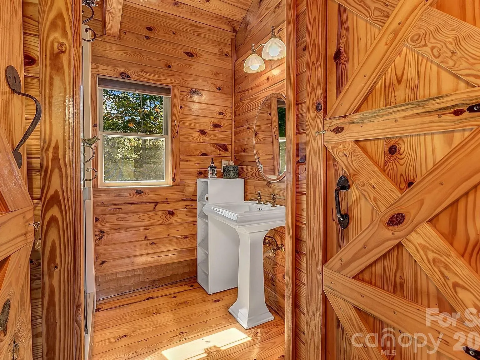 A powder room with a pedestal sink and a barn-style door