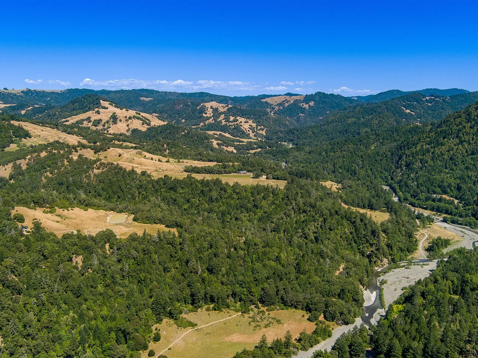 A wide aerial view of the surrounding vineyards, forest and river valley