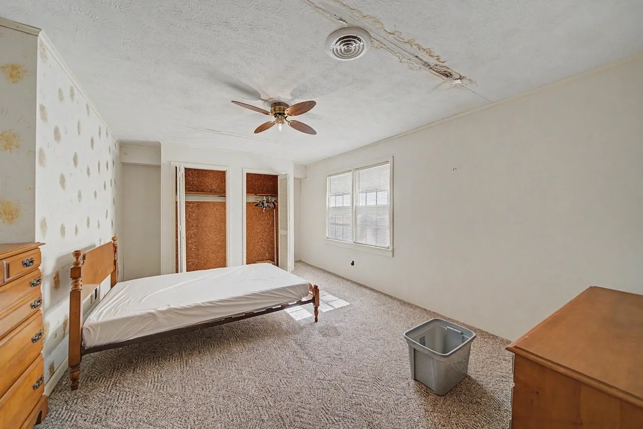 A bedroom with a bed, dresser and closet doors