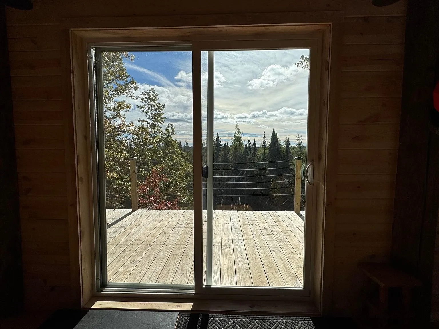 The sliding door onto the deck, forest beyond the glass