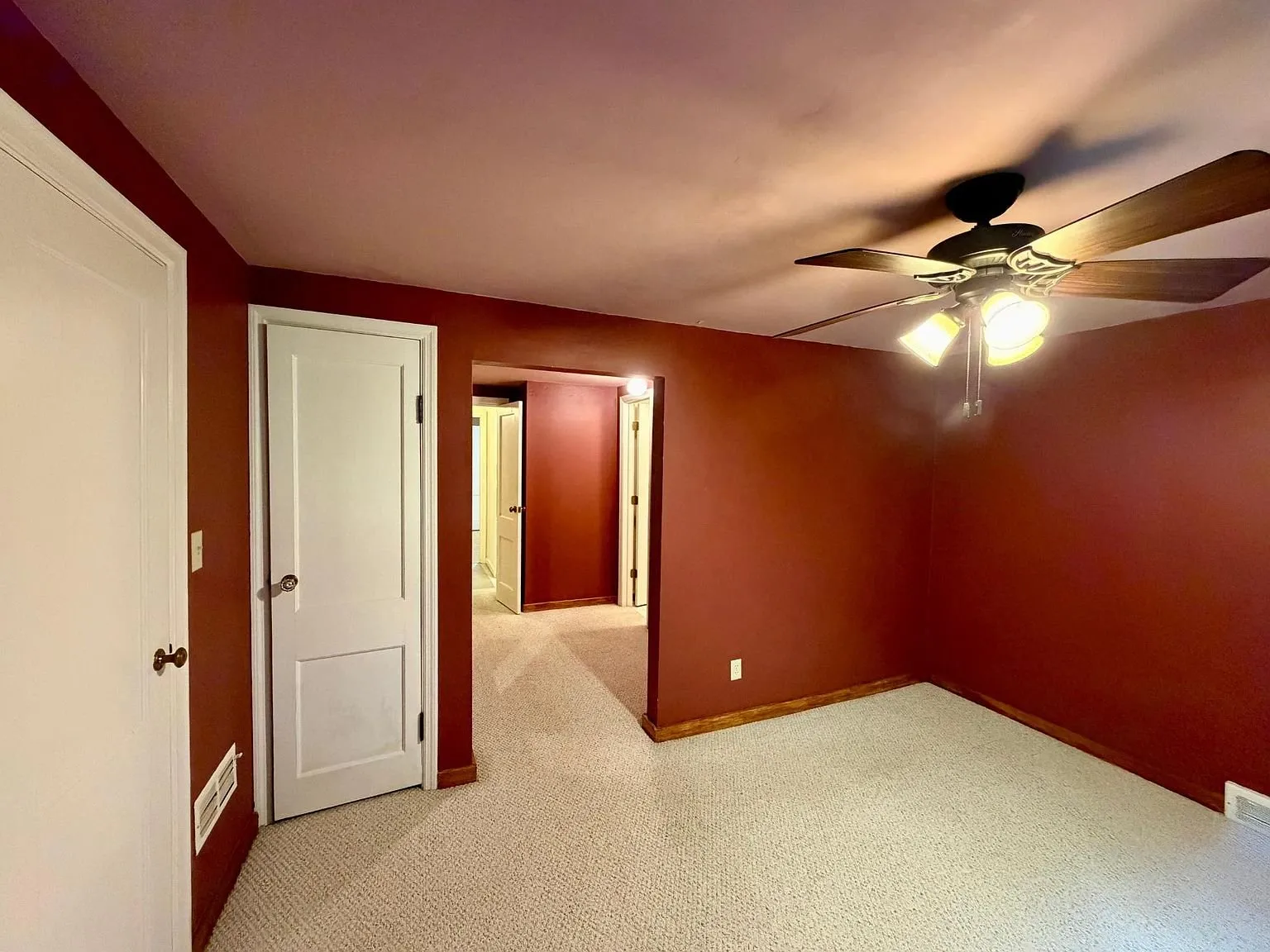 The red bedroom with the ceiling fan and the closet