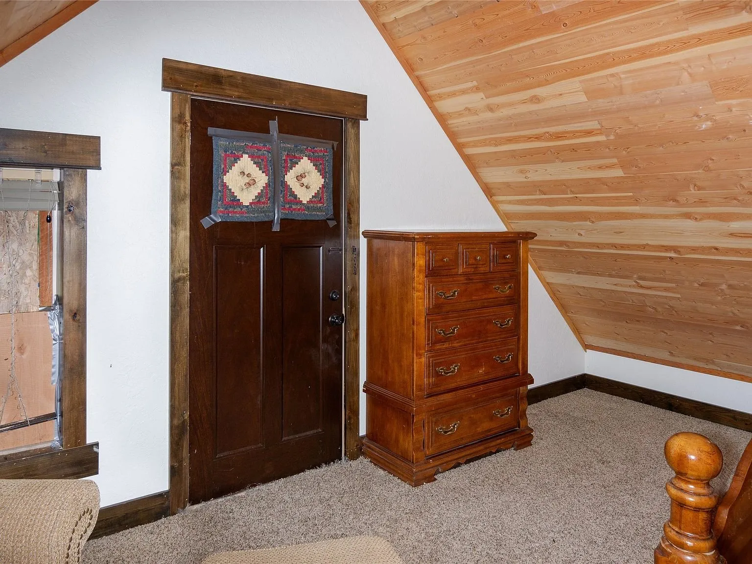 The loft's entry door and a chest of drawers beneath the sloped ceiling
