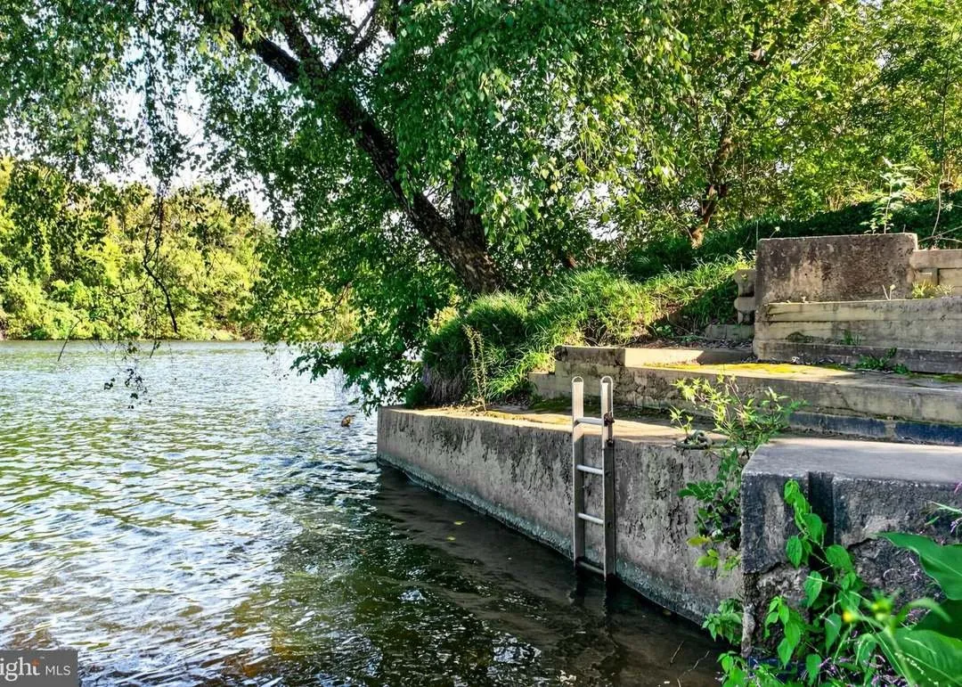 The river's edge with a concrete retaining wall and ladder down to the water