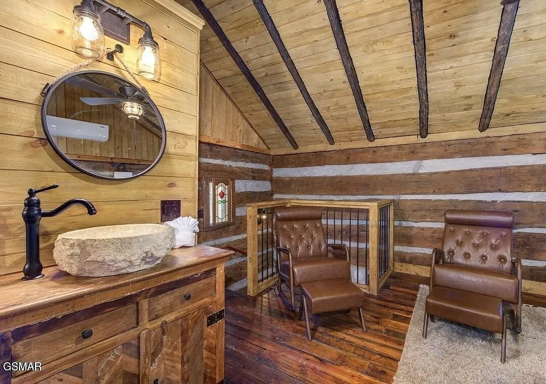 A bathroom with a stone vessel sink on a wood counter