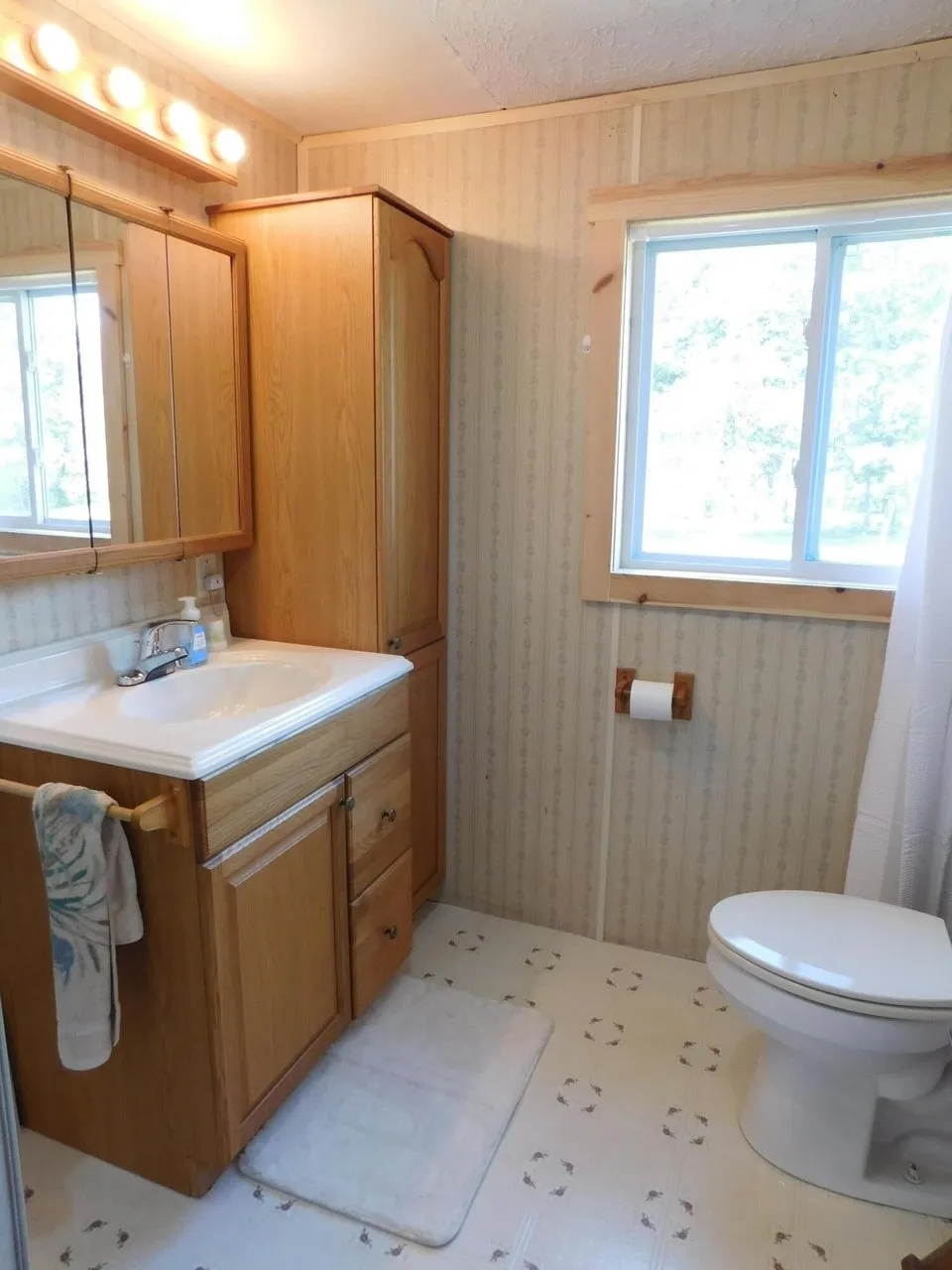 The bathroom with a vanity, mirror and toilet