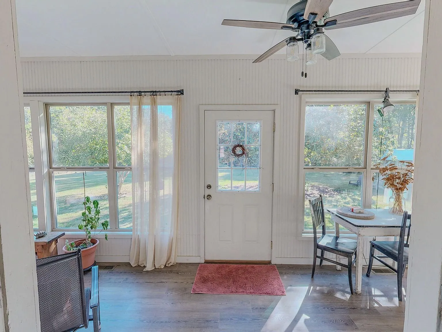The sunroom with windows on two sides, a small table and chairs
