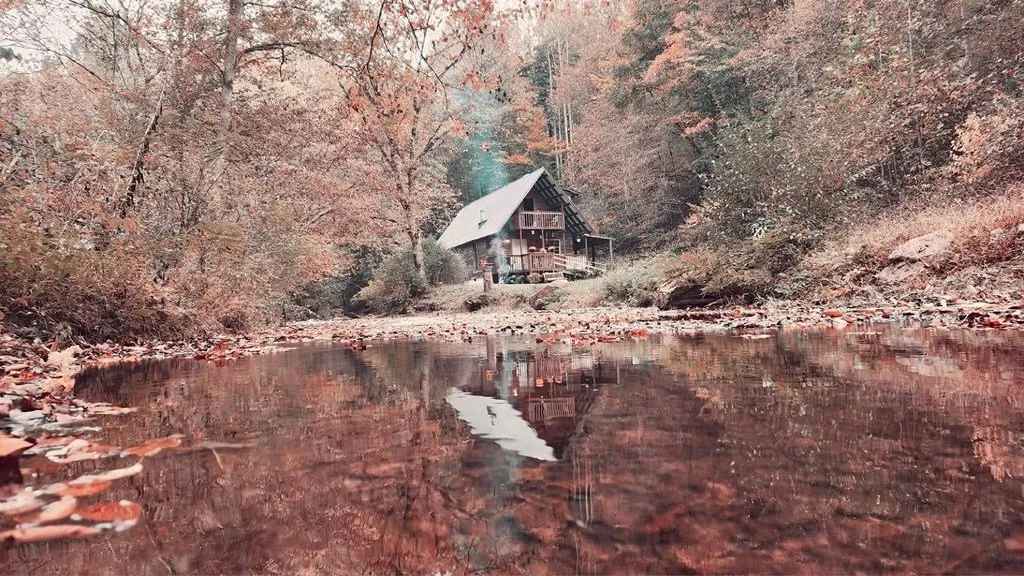 The cabin reflected in the creek on an autumn afternoon