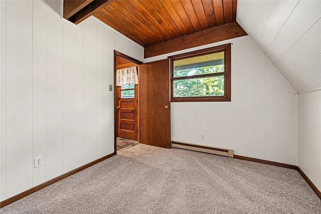 A bedroom with wood ceiling and skylight