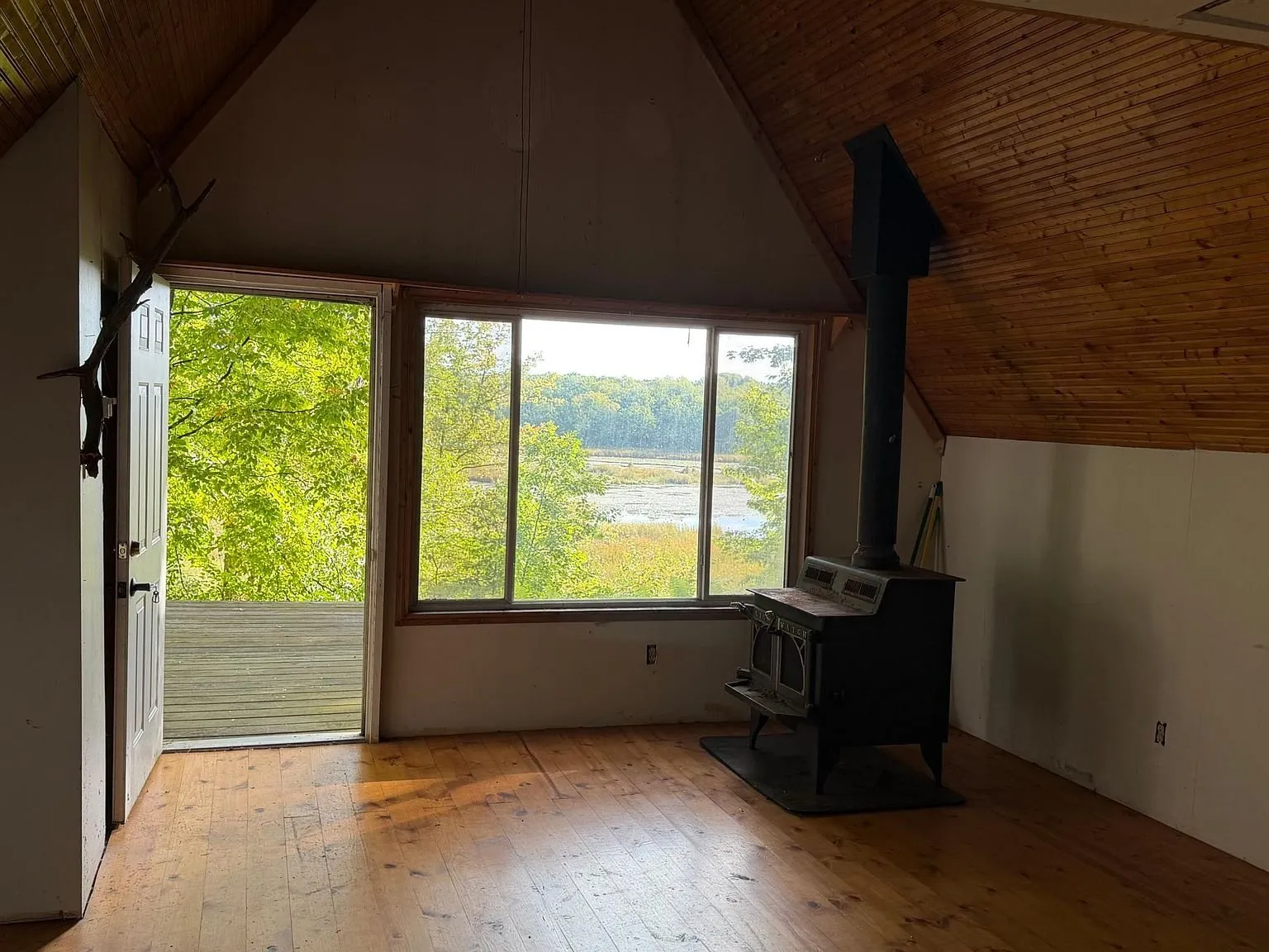 The glass door and the deck with the pond through the trees
