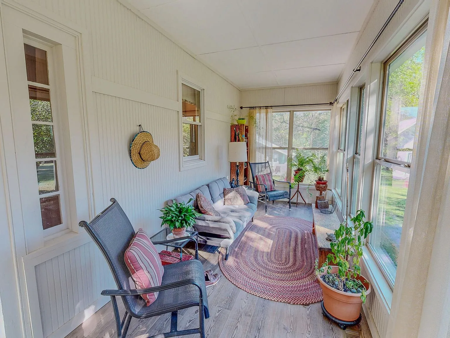 A second sunroom view with patio furniture and a braided rug