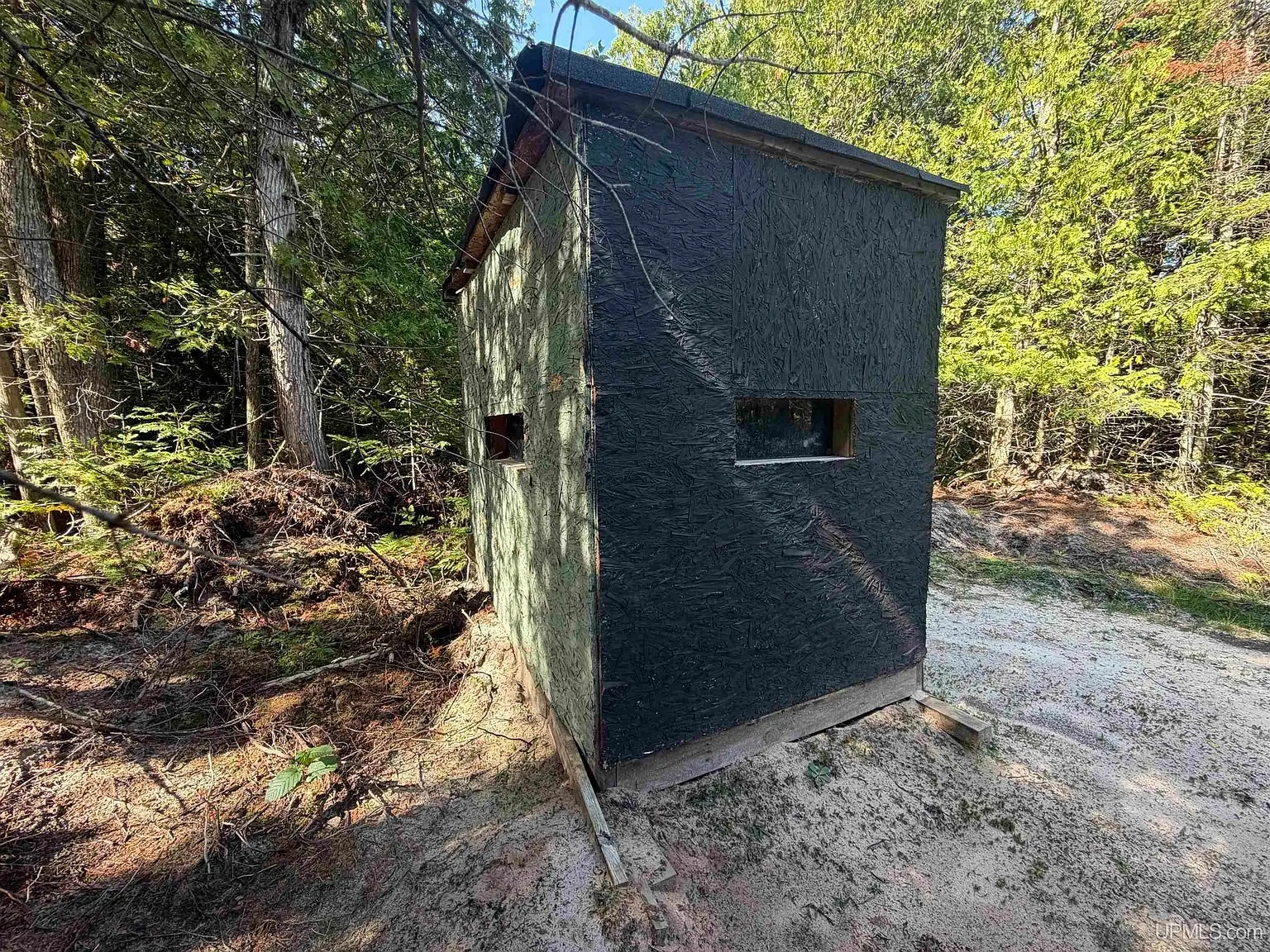 A ground blind at the edge of a sandy trail