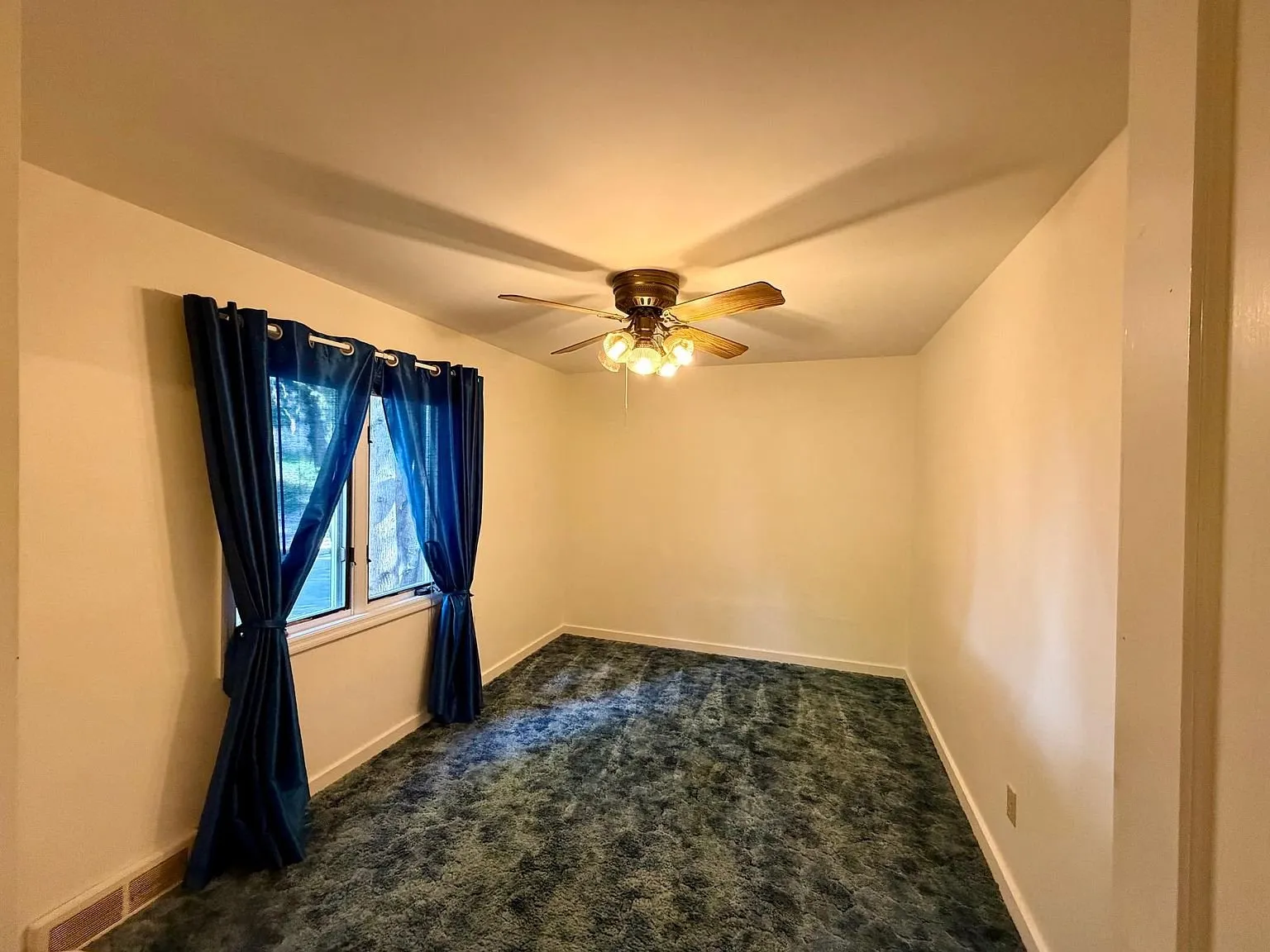 A bedroom with blue carpet and the window