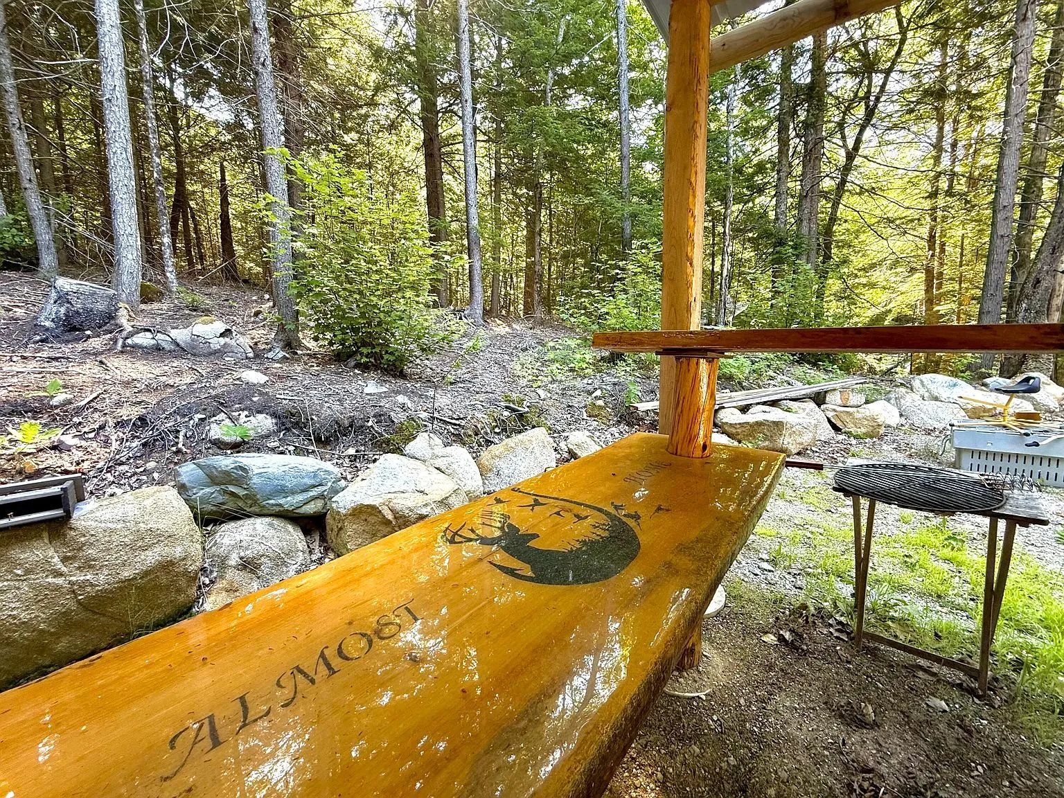The lean-to with the painted wooden bar and the boulders beyond