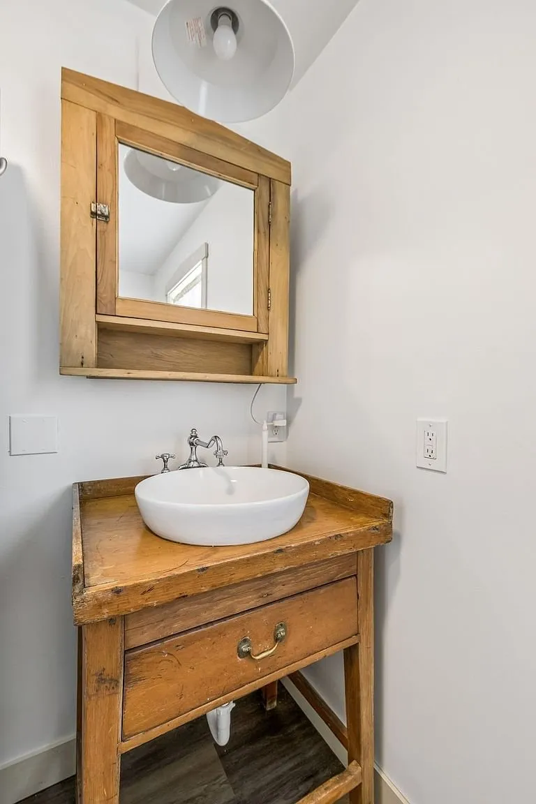A bathroom with the bowl sink on a wood vanity