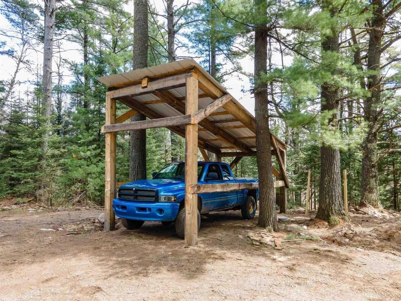 A timber frame carport with a truck parked under it