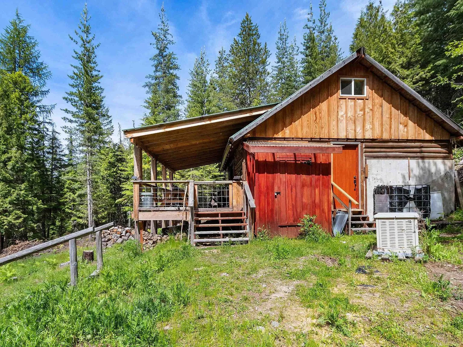 The outbuilding and cabin's covered deck, seen together from the sloped yard