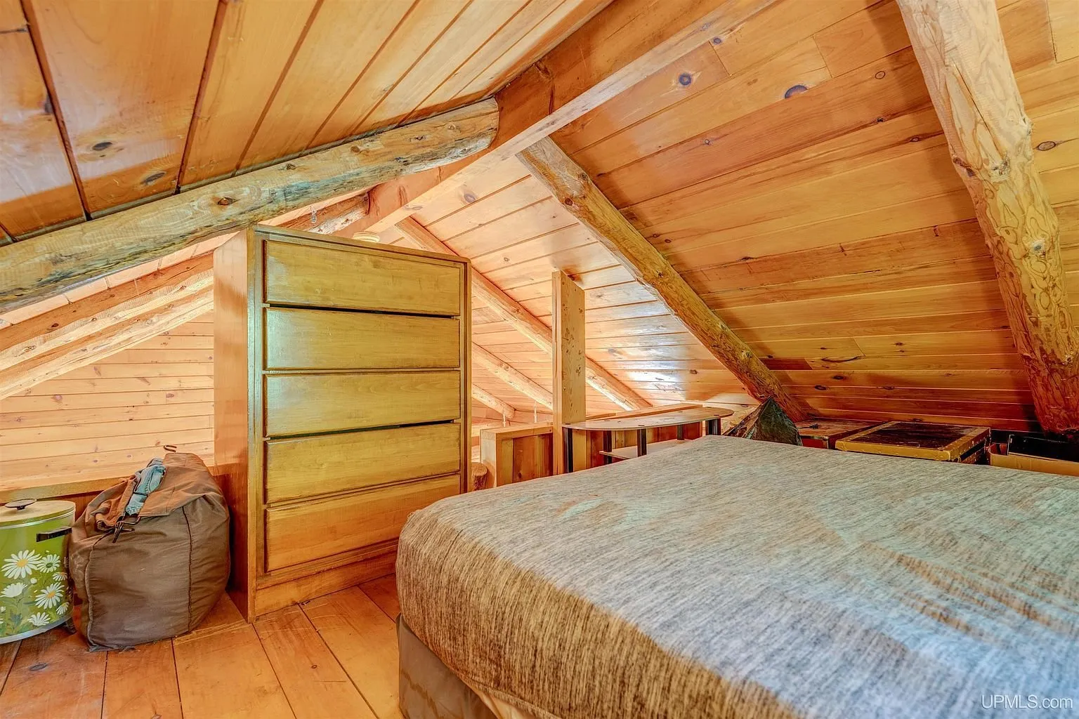 The loft bed and dresser under the rafters