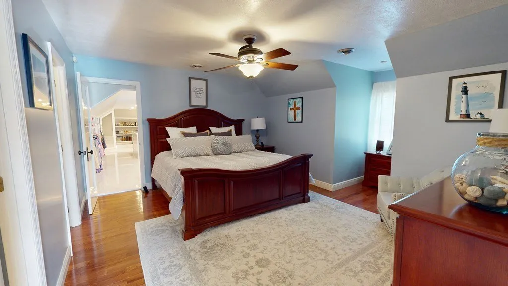 A bedroom with pale blue walls and a ceiling fan