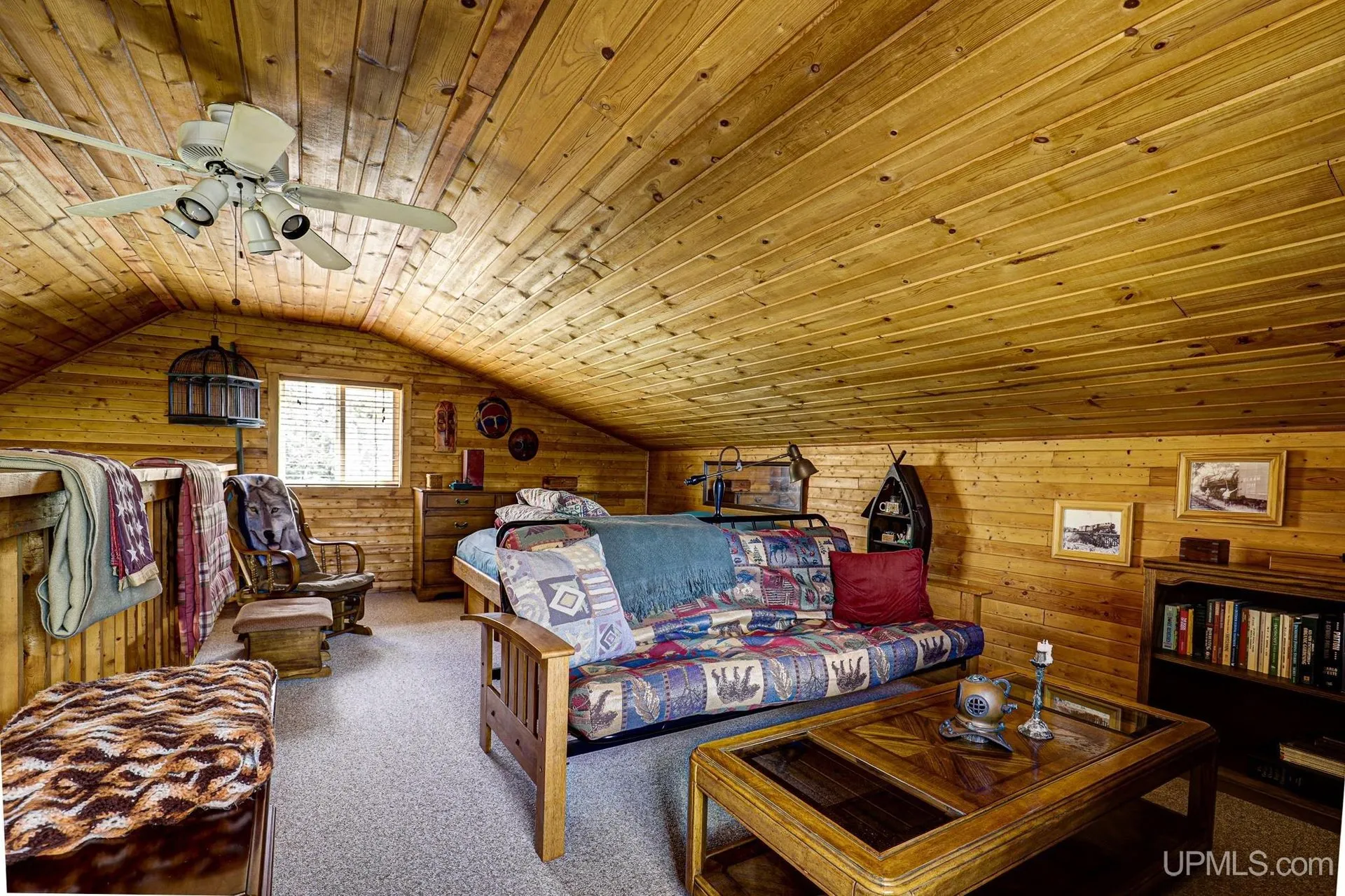 The loft sitting area under the roof with a ceiling fan
