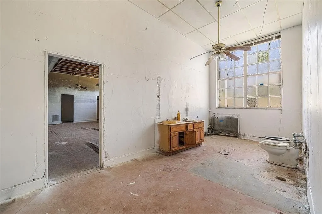 A room with the ceiling fan, the cabinet, the radiator and the toilet on the floor