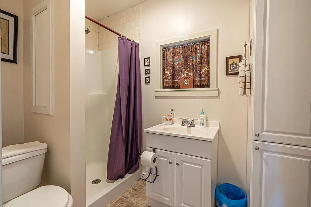 A hallway with a wall-mounted microwave, AC unit and the second bathroom beyond