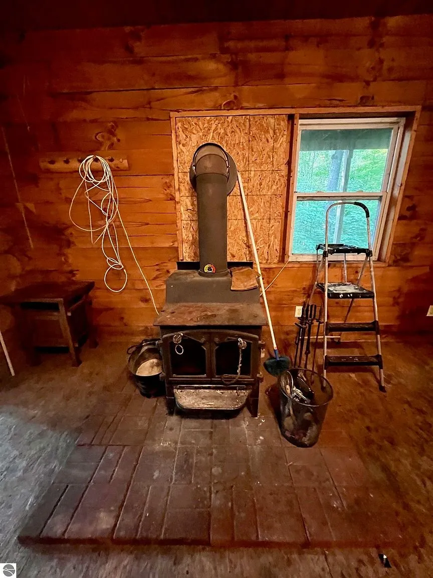 The basement with the barrel stove and its pipe through the plywood panel