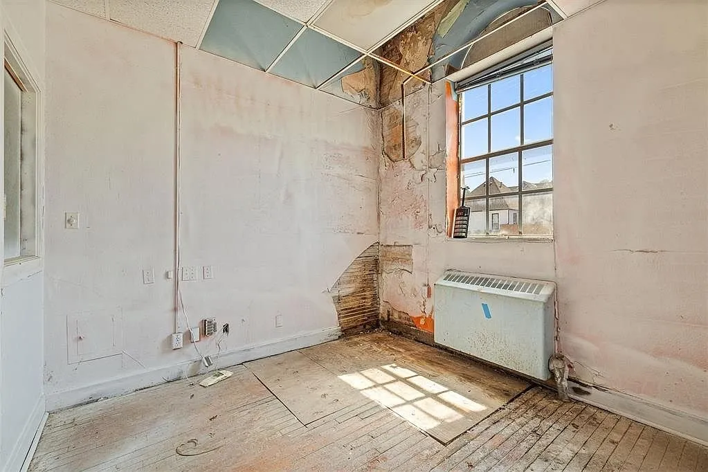 A corner with the water-stained wall, the radiator and the ceiling coming down