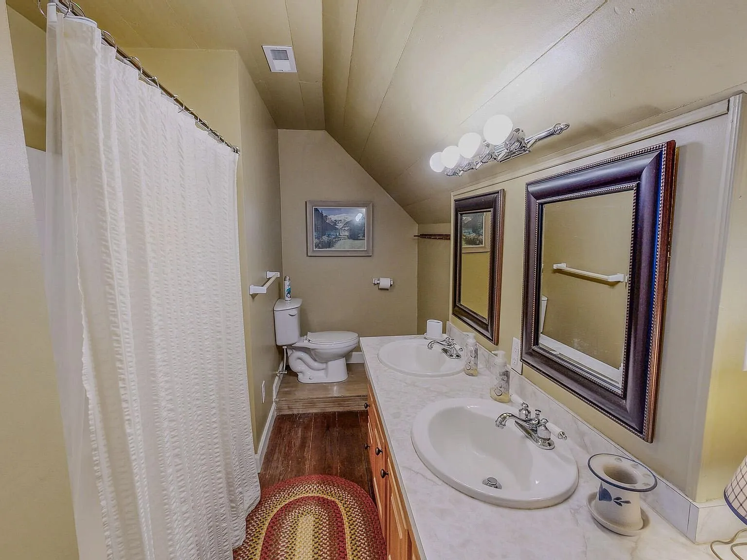 A bathroom with a pedestal-style vanity, mirror and clawfoot-style tub
